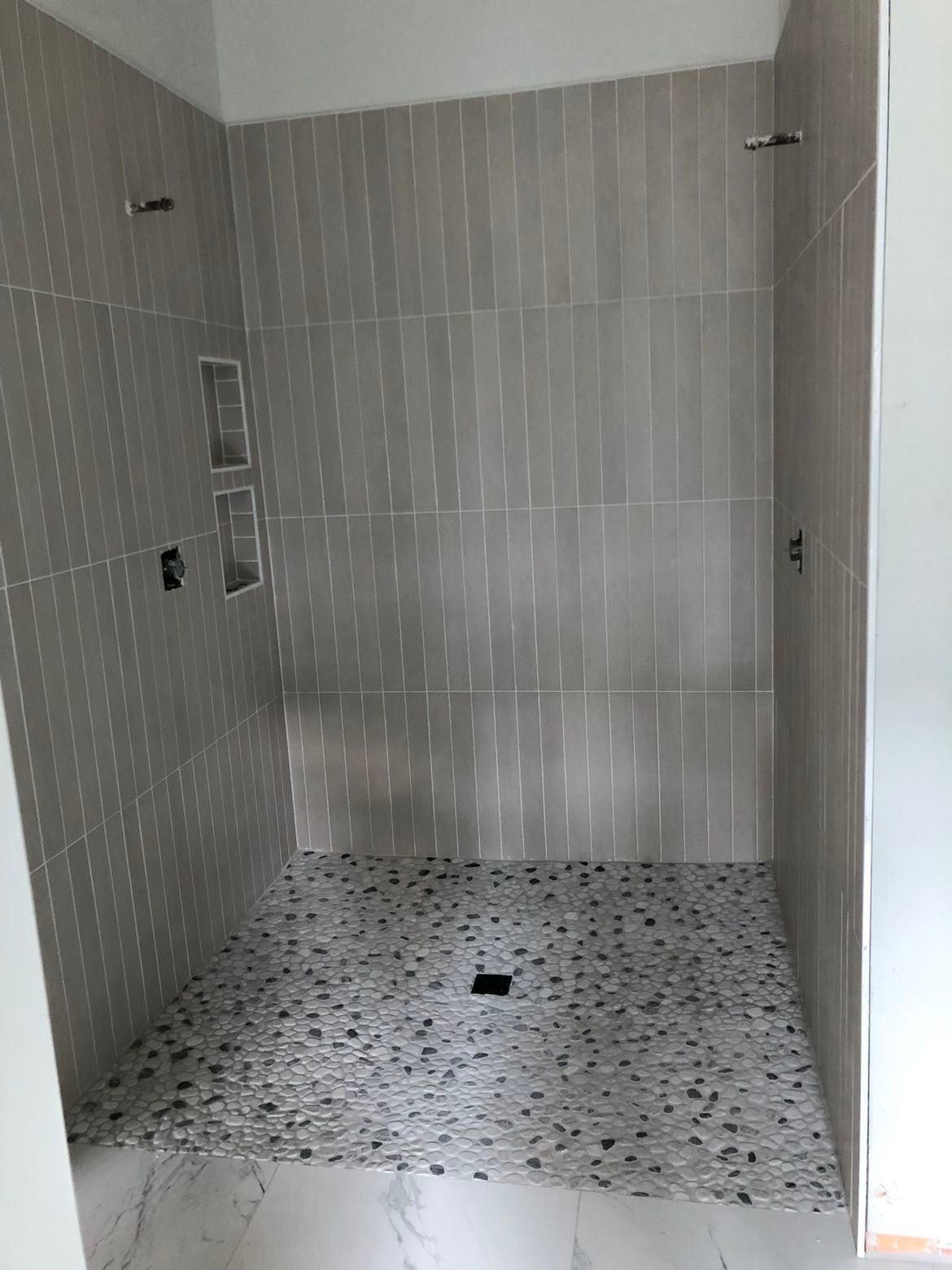 A bathroom with a walk in shower and a tiled floor.