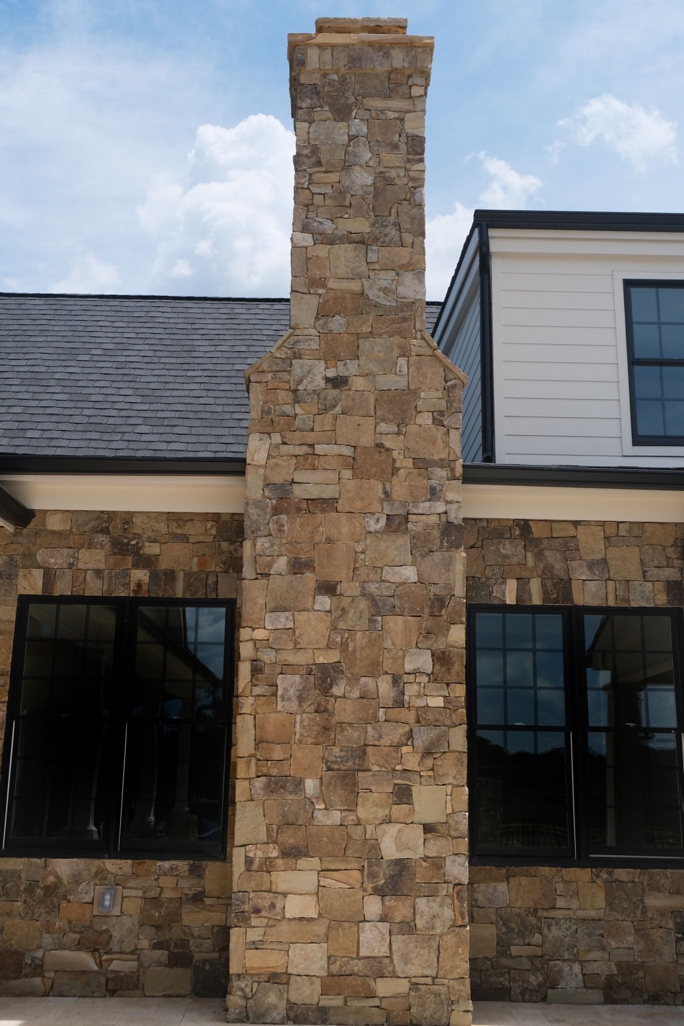 A large stone chimney is on the side of a house.
