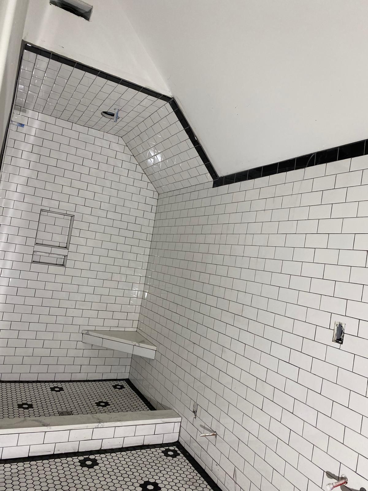 A bathroom with white brick walls and black trim