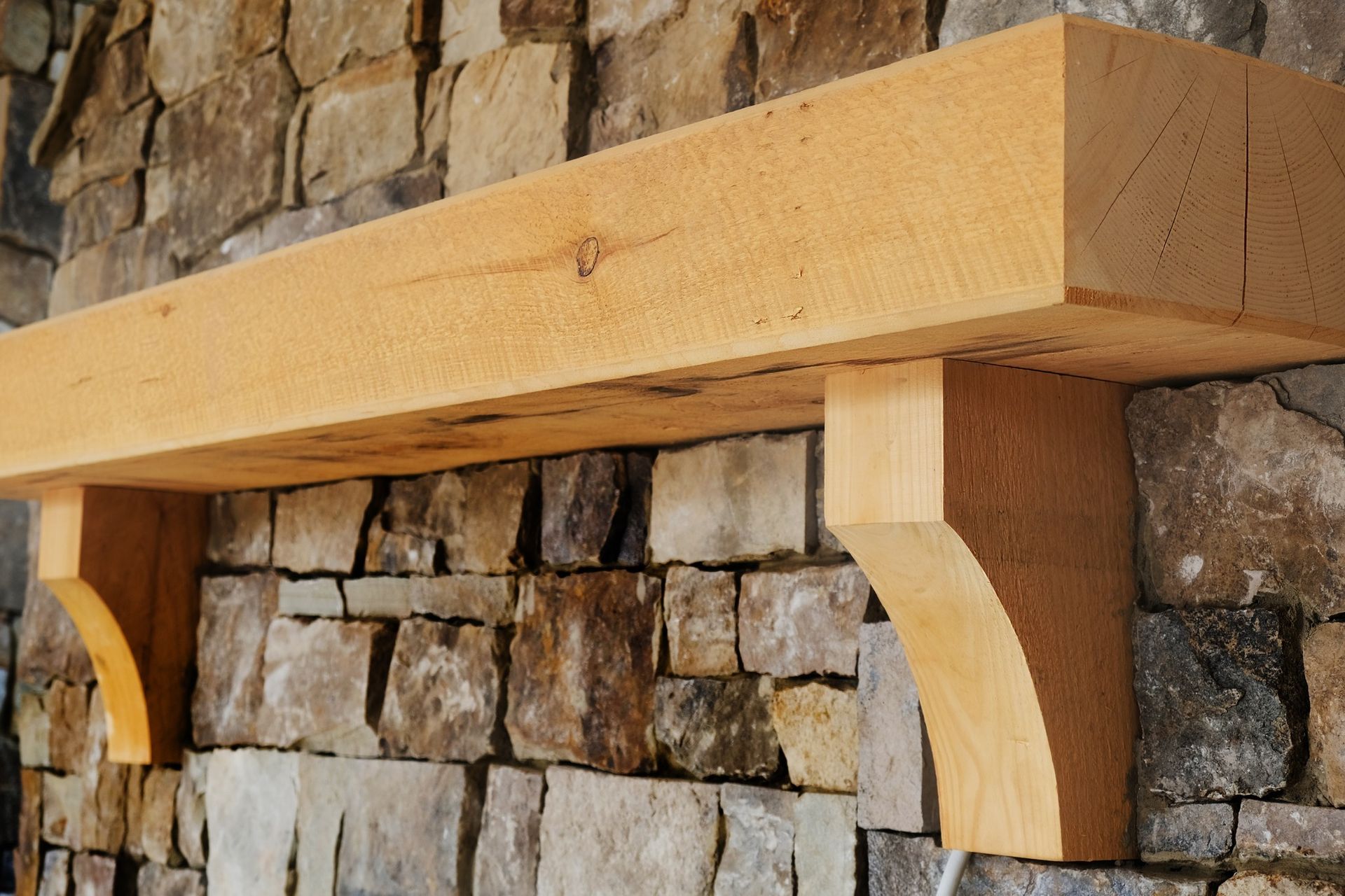 A wooden mantle is mounted to a stone wall