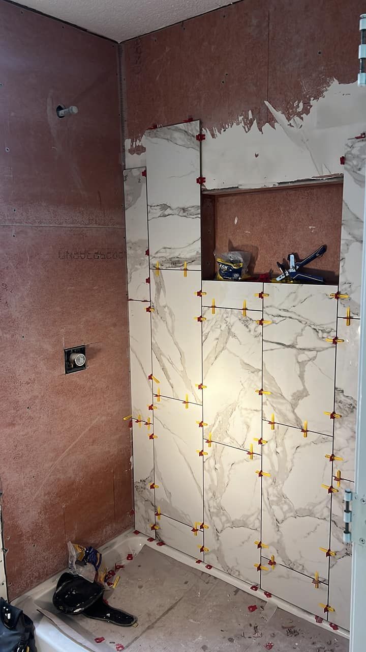 A bathroom with marble tiles being installed on the wall.