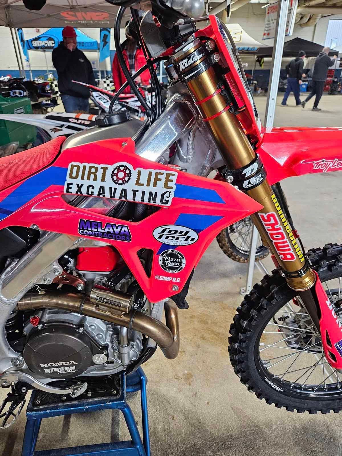 A dirt bike is parked on a stool in a parking lot.
