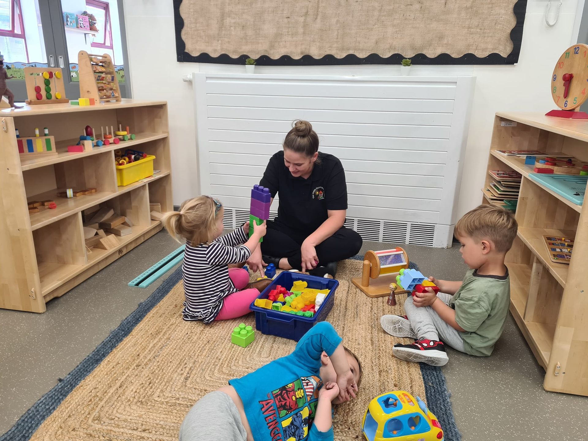 A woman is sitting on the floor playing with children.