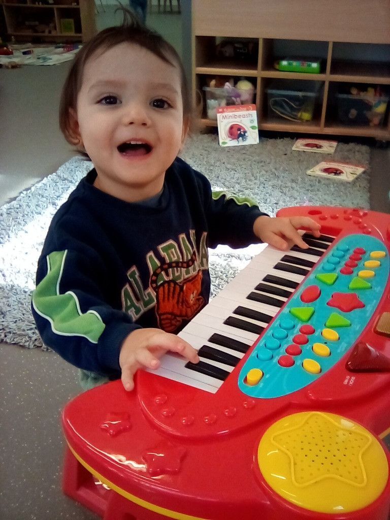 A young boy wearing an alabama shirt is playing a toy piano