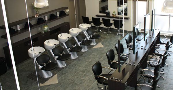 Hair salon interior with styling stations, sinks, and seating.