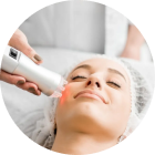 Woman receiving red light therapy facial treatment.