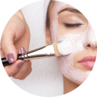 Person receiving facial mask treatment; hand applying mask with brush.