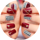 Hands displaying burgundy and black and white patterned nail art. Gold accents are included.