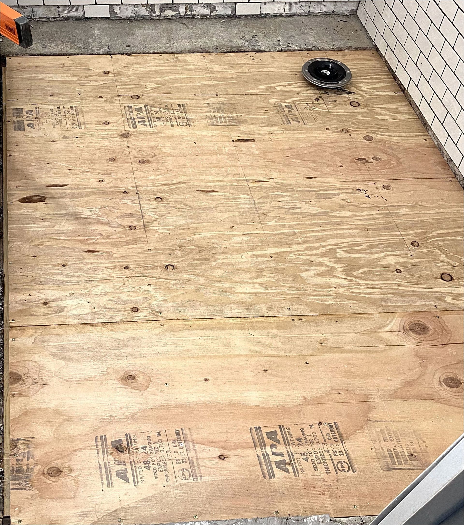 A person is working on a wooden floor with a drill.