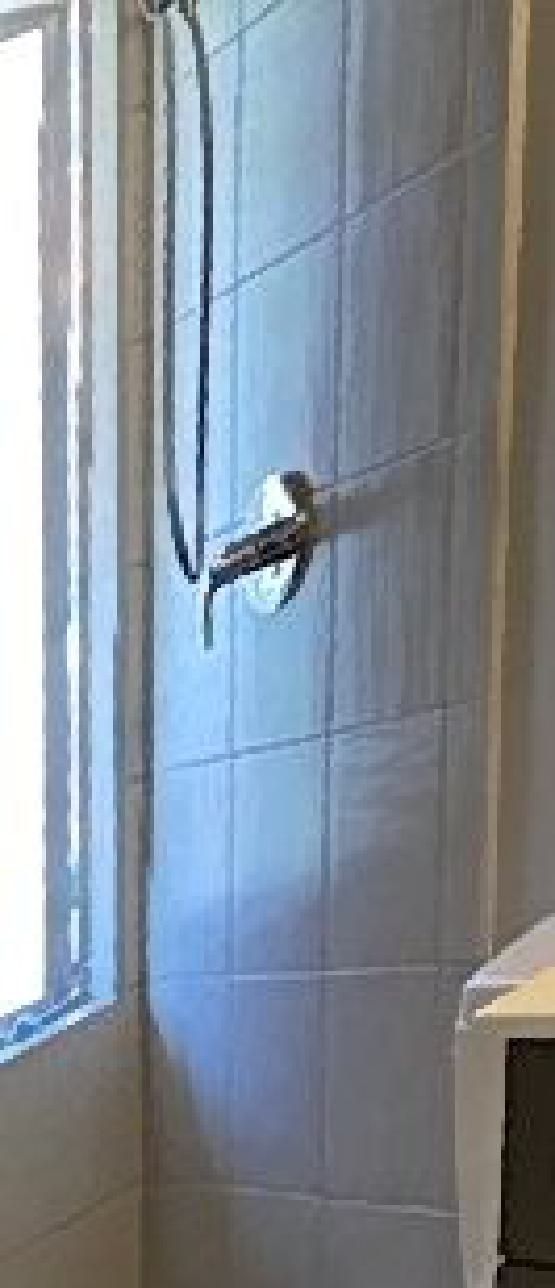 A bathroom with a shower head and a window.