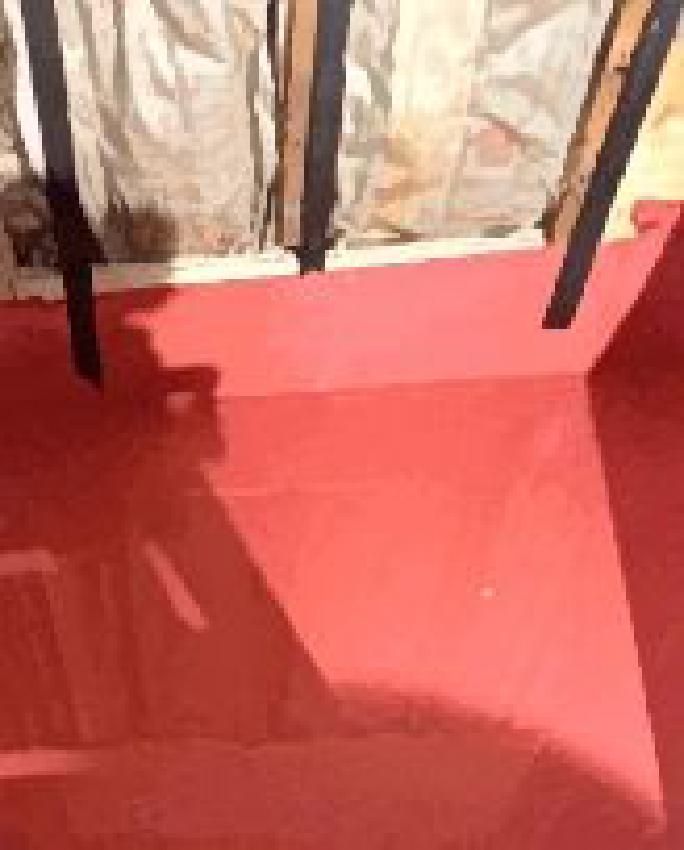 A red floor with a shadow of a person on it.