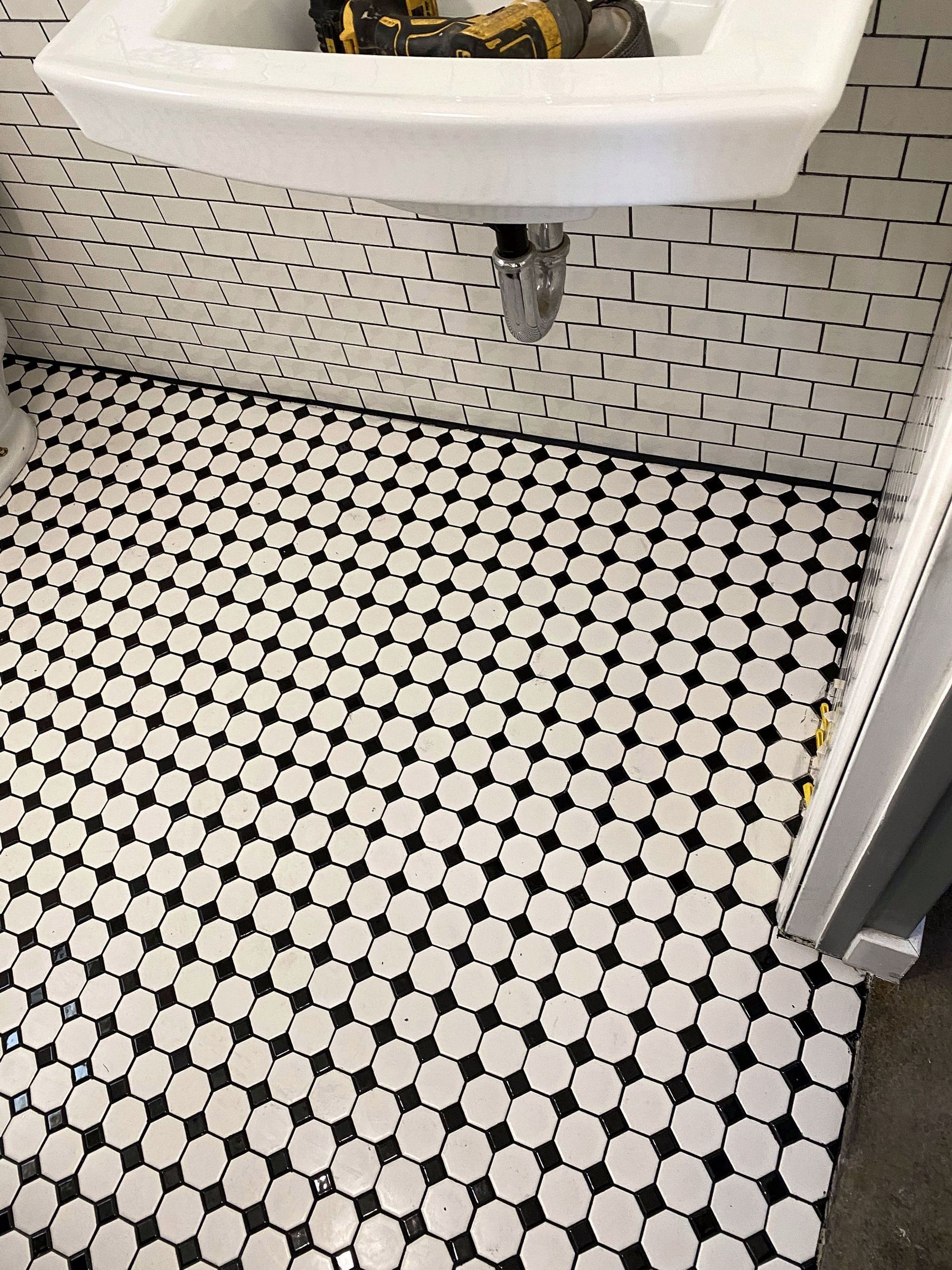 A bathroom with a sink and a black and white tile floor.