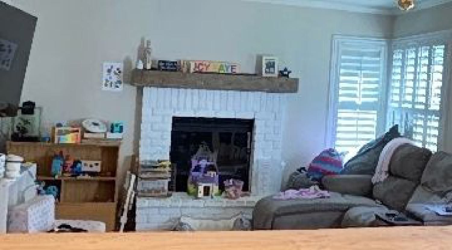 A living room with a couch , fireplace and shutters.