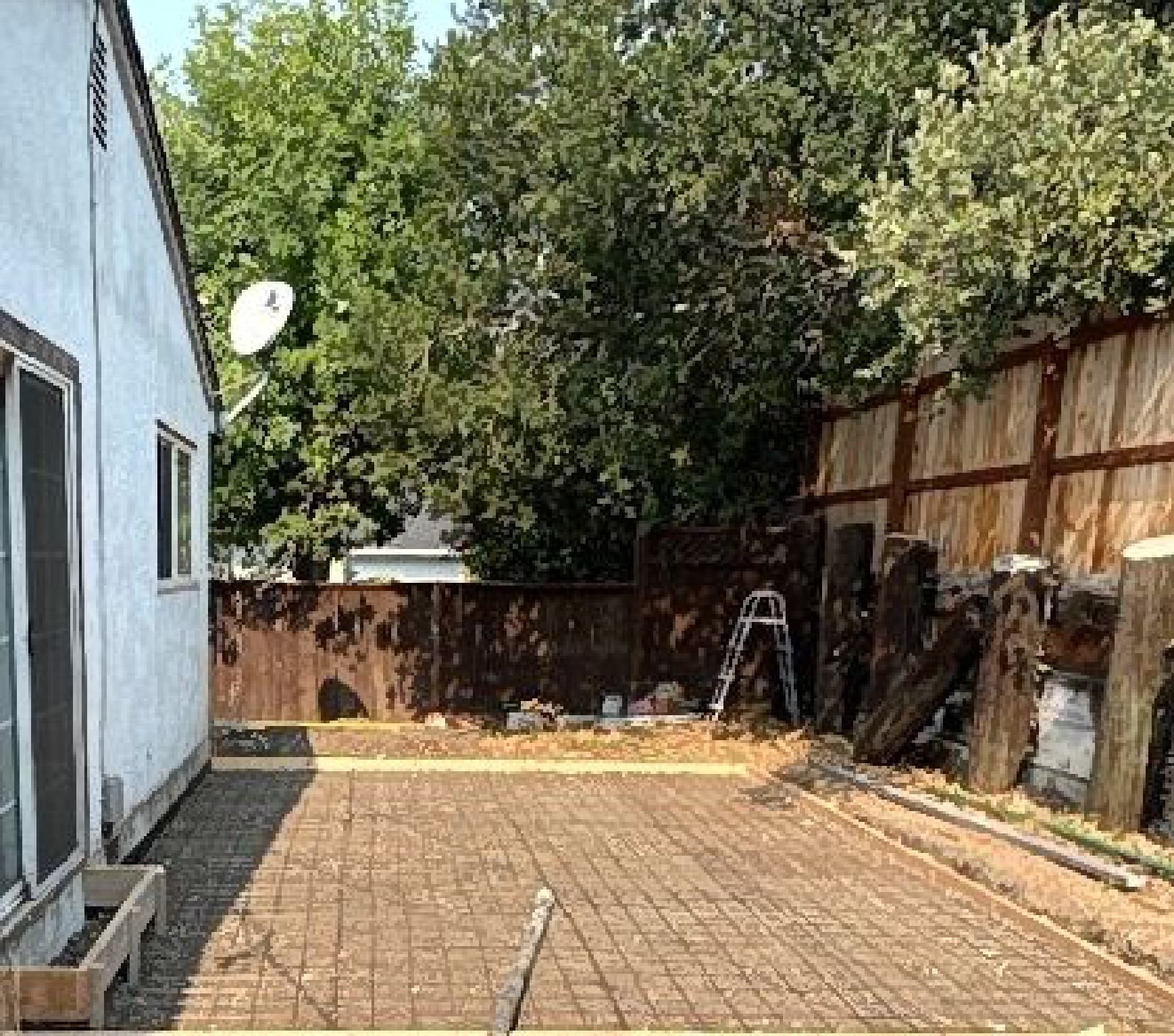 A concrete patio is being built in the backyard of a house.