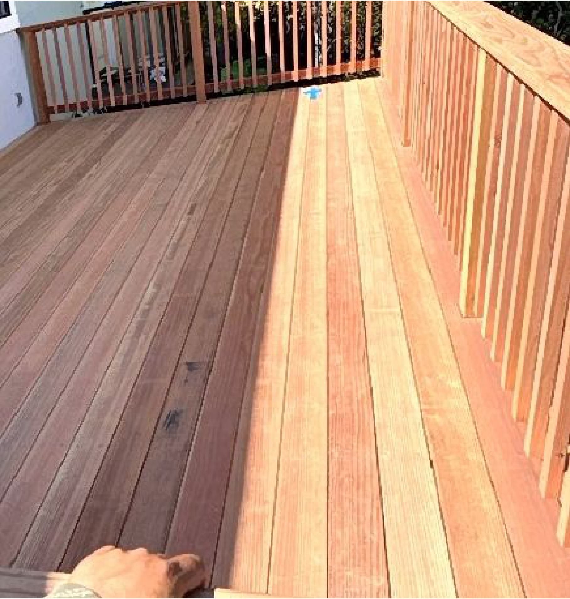 A person is standing on a wooden deck with a railing.