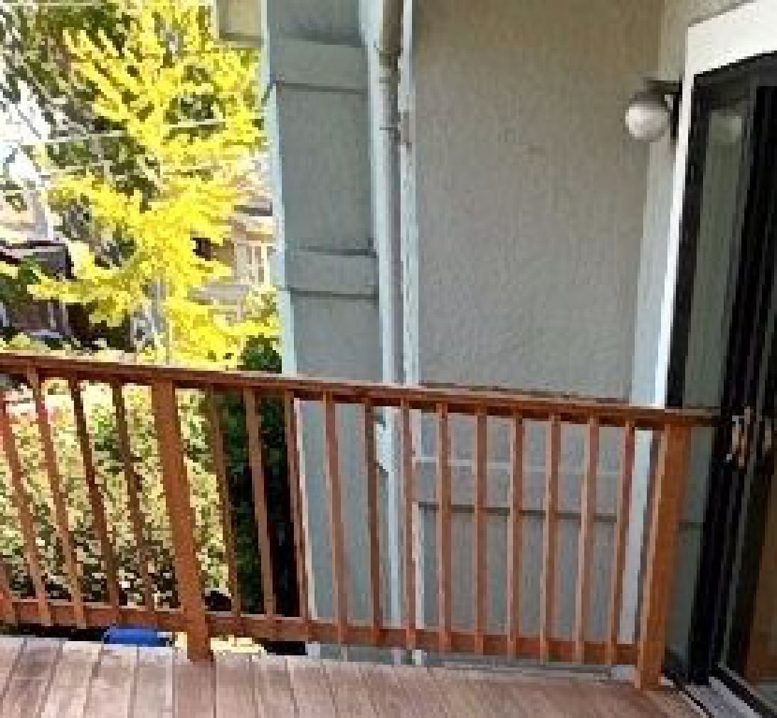 A balcony with a wooden railing and a sliding glass door