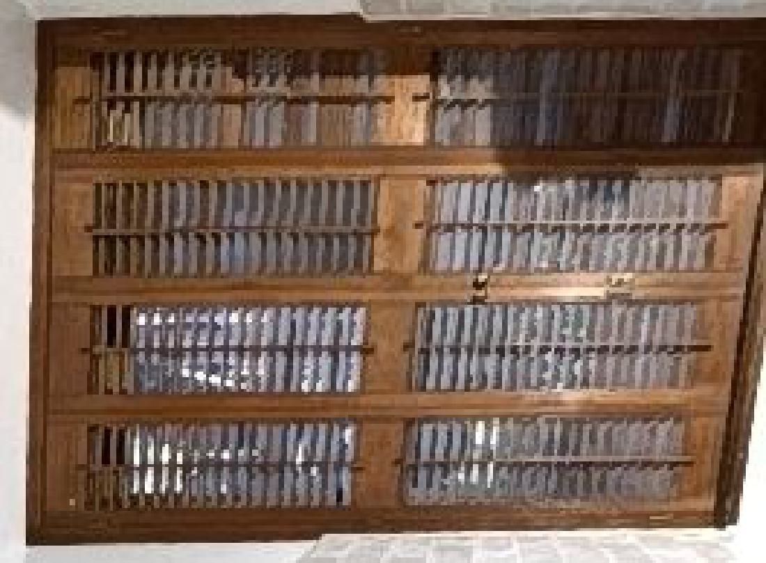 A wooden shelf with a lot of books on it is hanging on a wall.