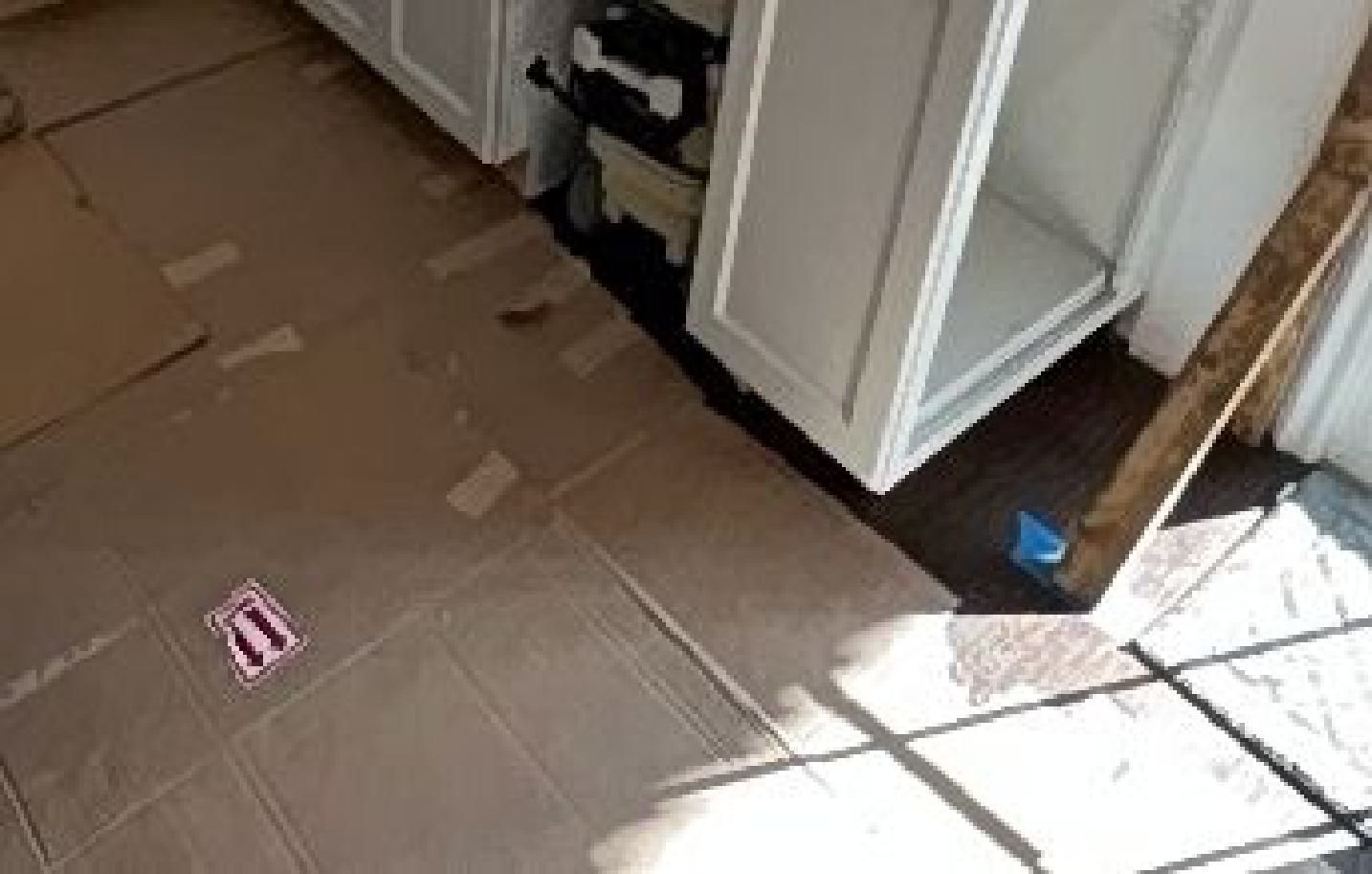 A cardboard box is sitting on the floor in a kitchen.
