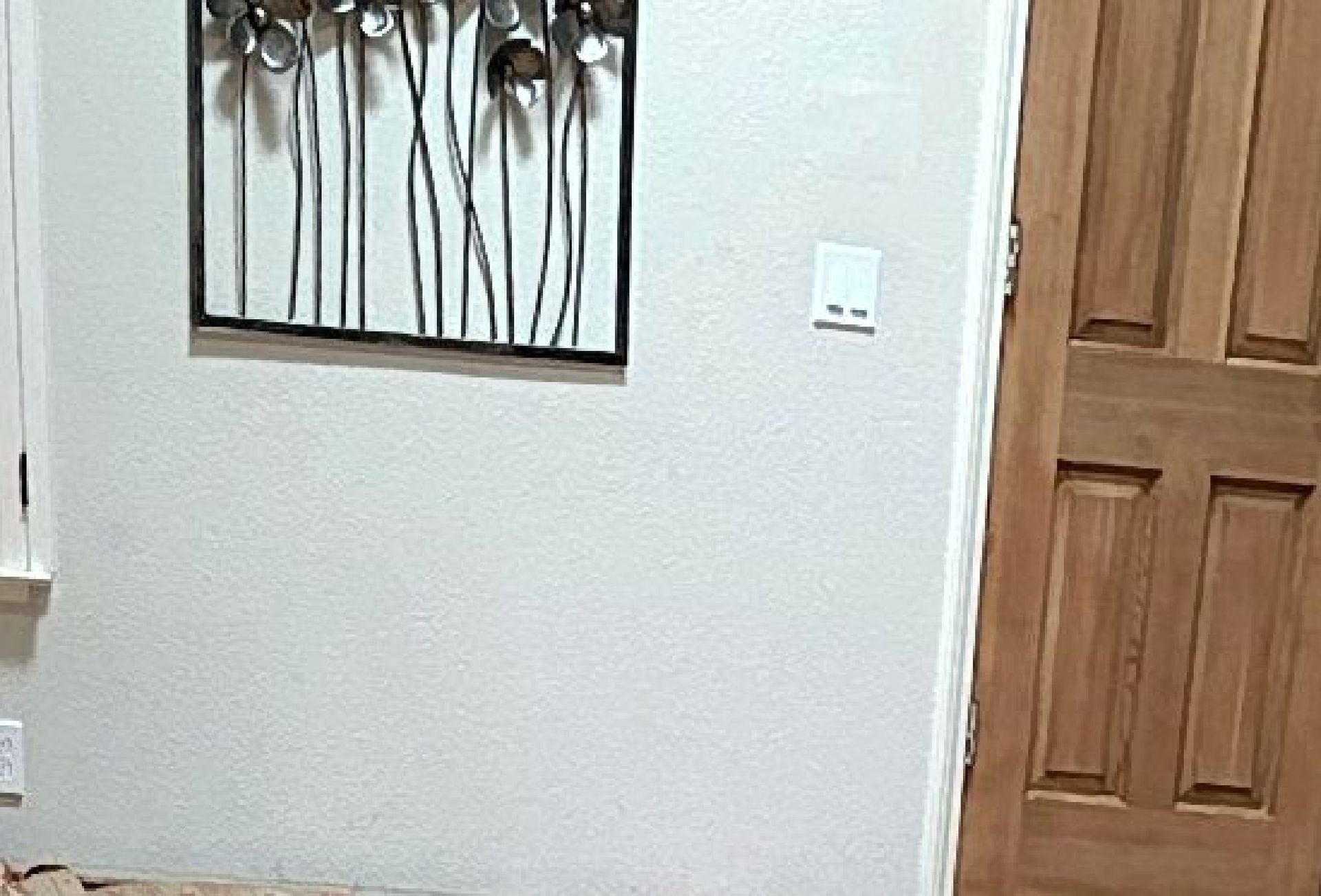 A hallway with a wooden door and a painting on the wall.