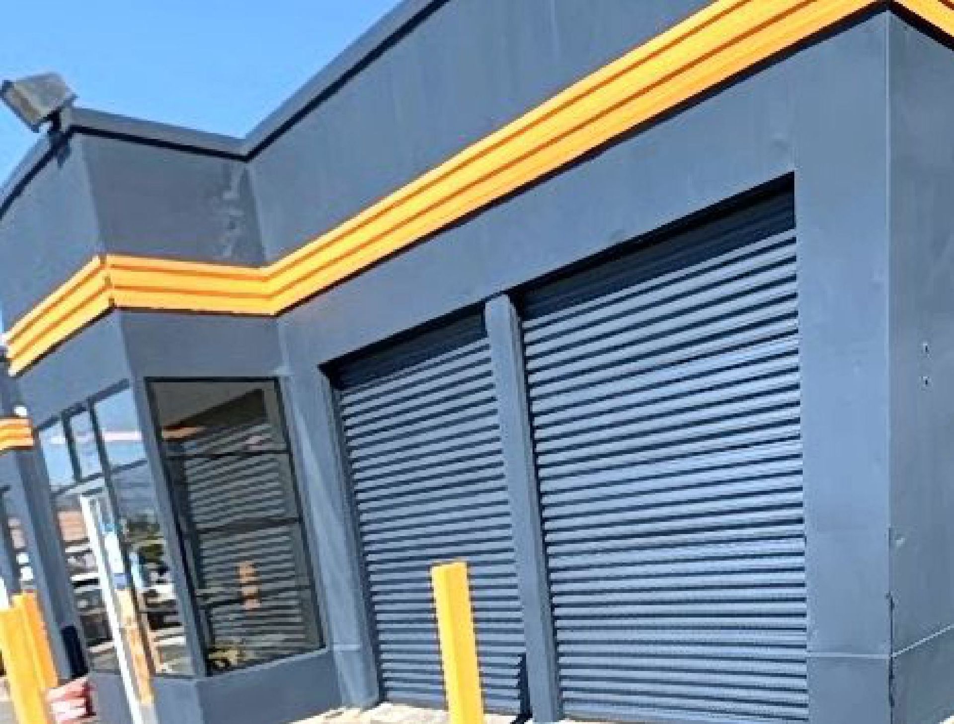 A black building with yellow trim and shutters on the doors