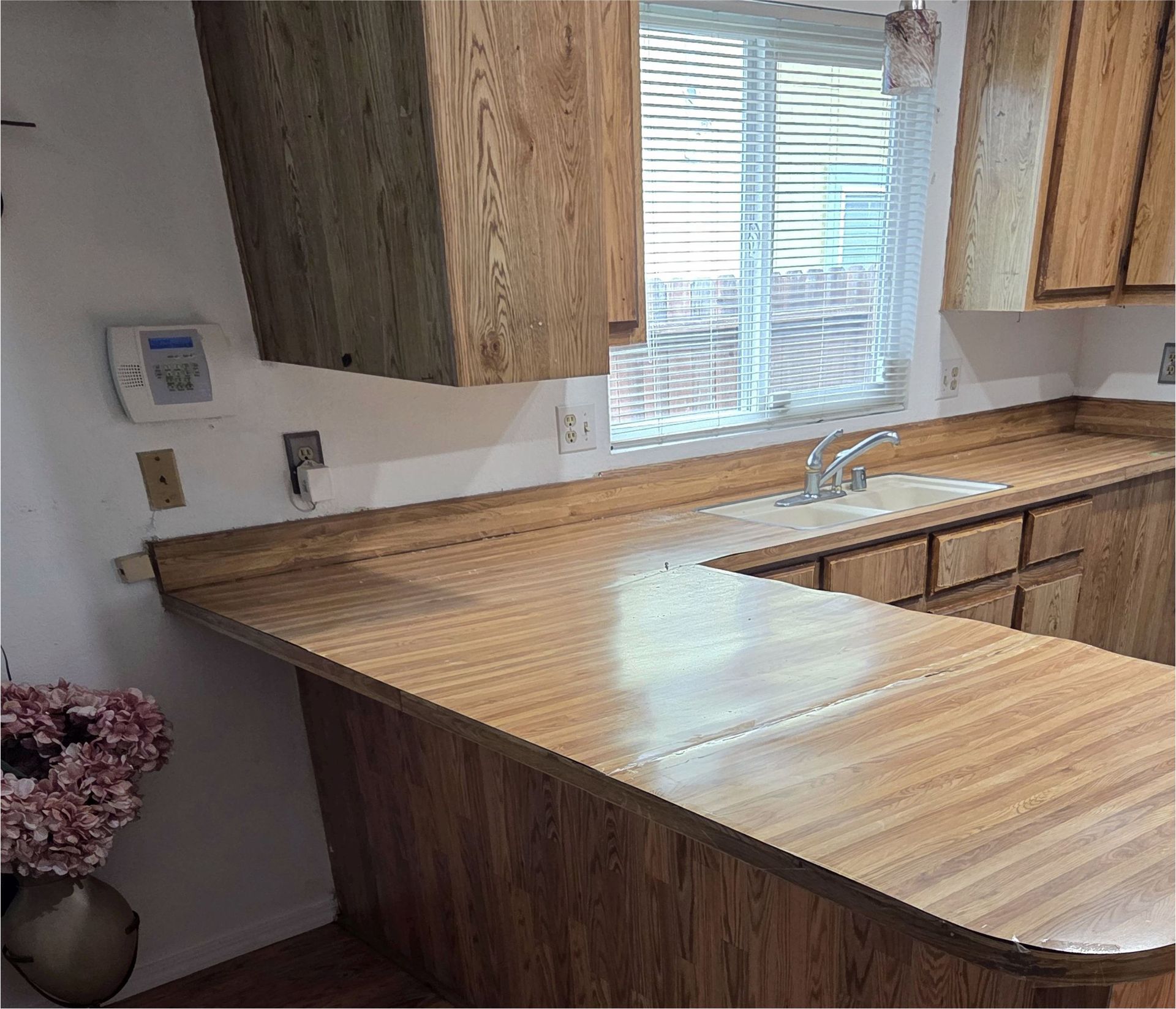 A kitchen with wooden cabinets , a sink , and a window.