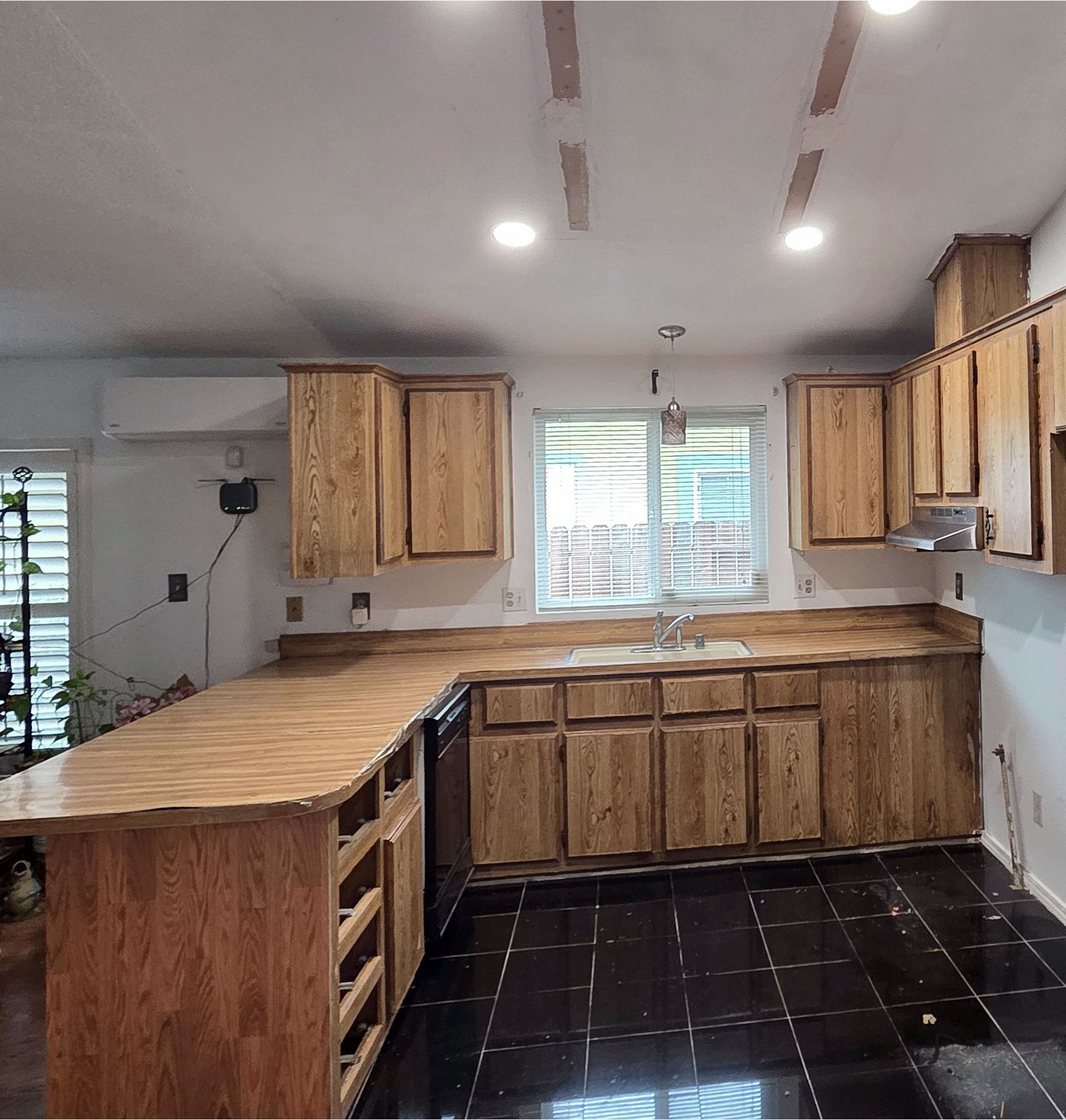 A kitchen with wooden cabinets and black tile floors