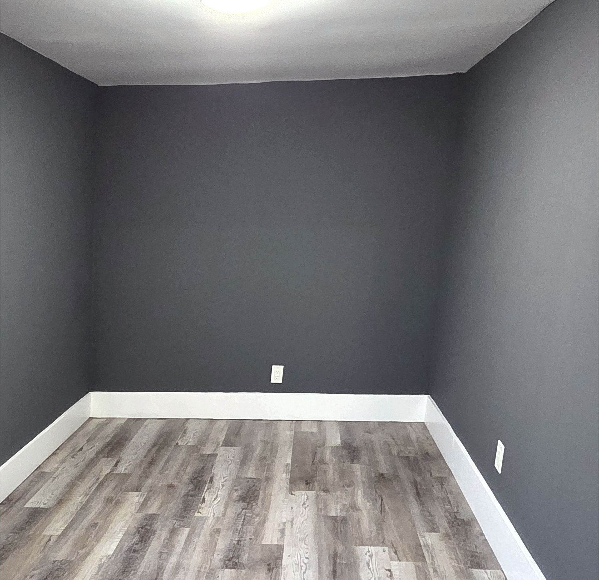An empty room with gray walls and a wooden floor