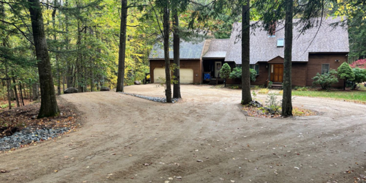 Row of white houses with green lawns and trees, sunny day.