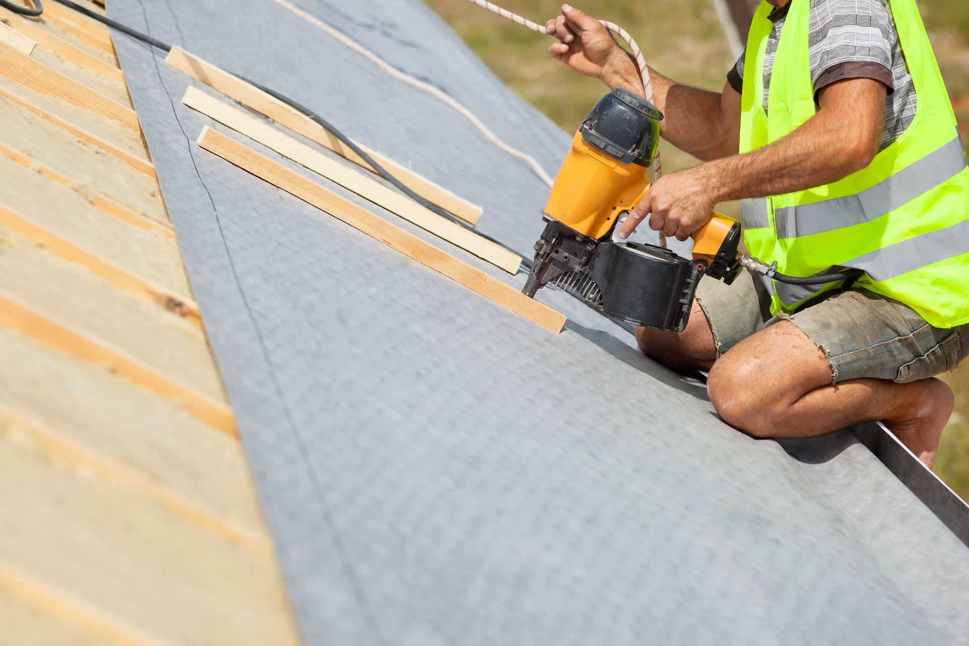A construction worker is holding a wooden beam over his head.