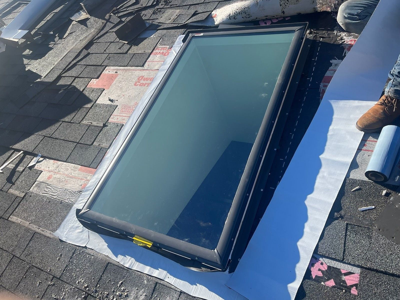 A man is installing a skylight on the roof of a building.