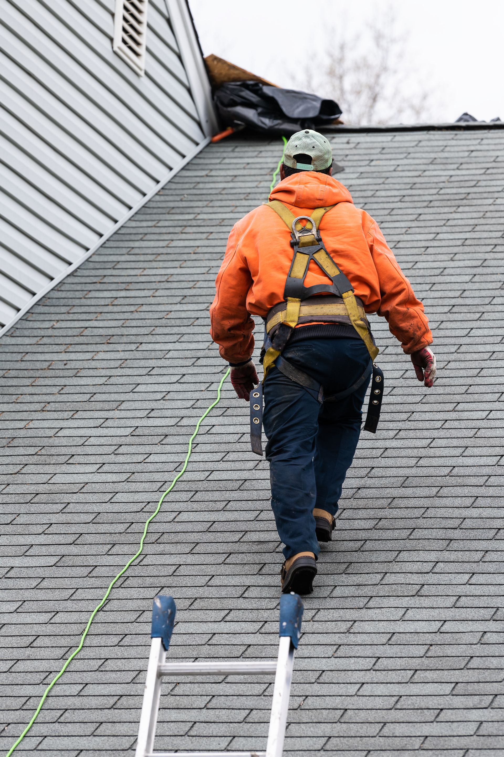 A man is walking up a ladder on a roof.