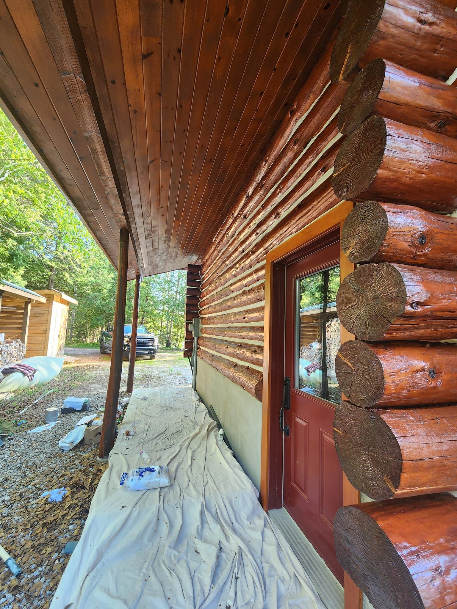 The side of a log cabin is being painted.