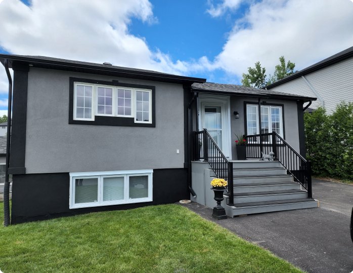 A gray and black house with stairs leading up to the front door.