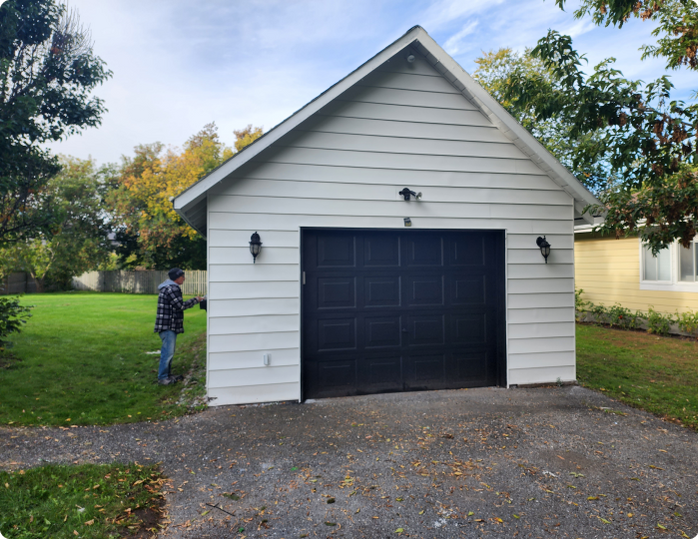 A man is standing in front of a white garage with a black door