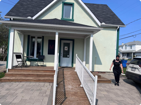 A woman walking in front of a house with a ramp