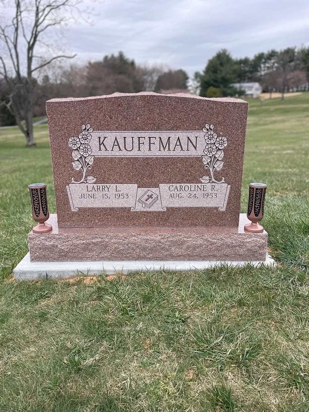 A granite Kauffman family headstone with engraved names and dates, positioned on a grassy cemetery lawn.