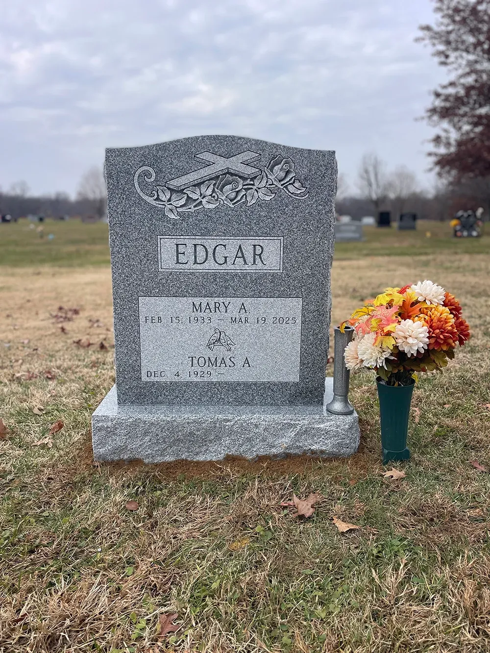 A grey granite tombstone engraved with the surname 