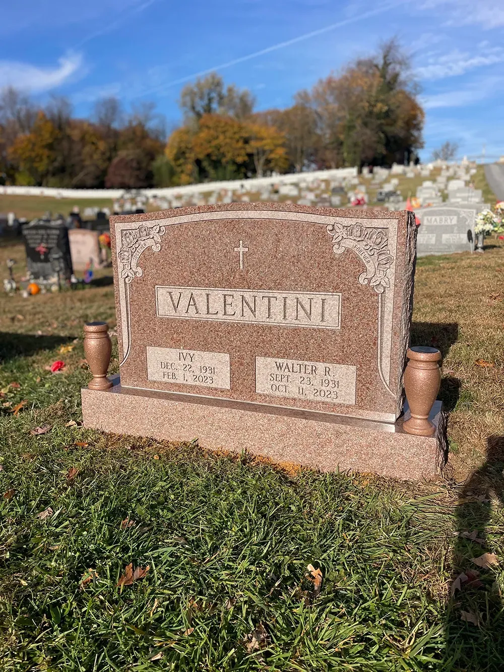 A pinkish-brown granite gravestone with the name 