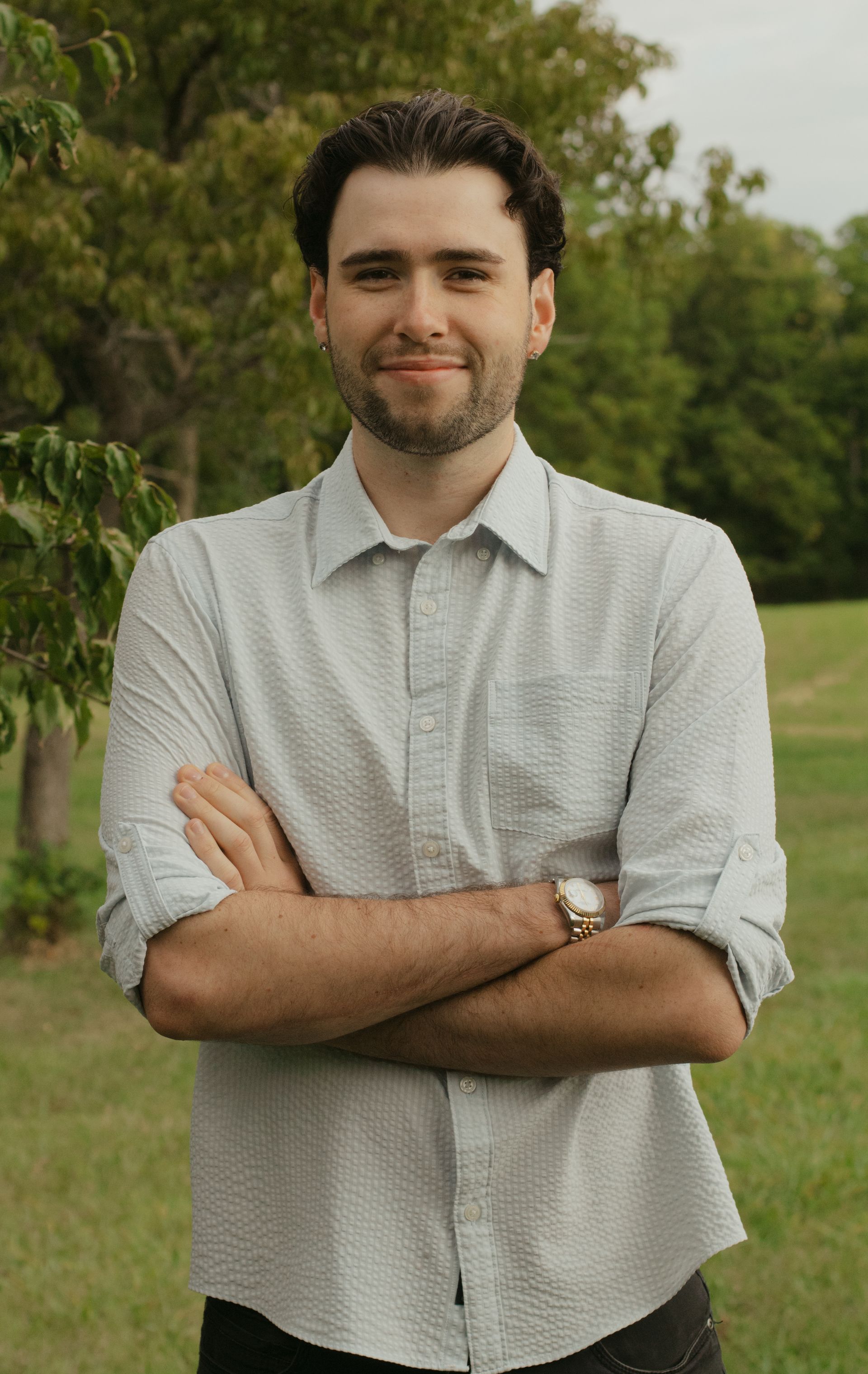 Man in a suit smiling, wearing a white turtleneck in a kitchen setting.