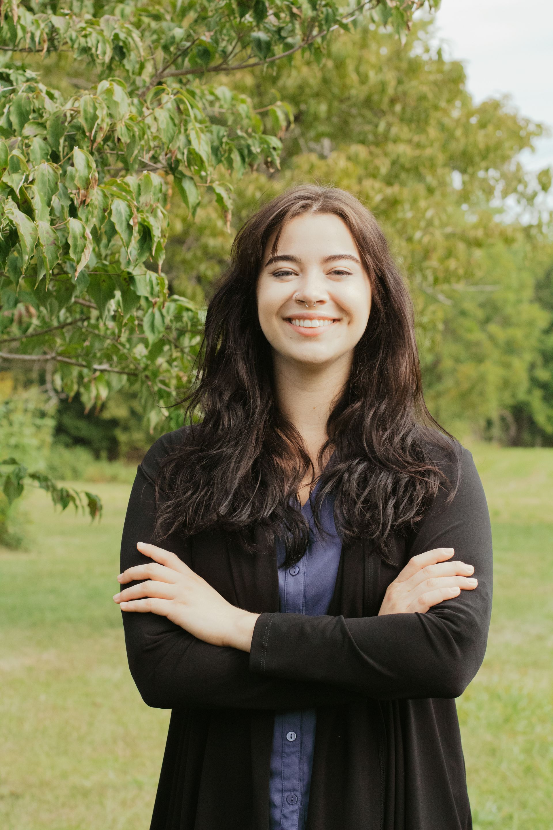 Woman wearing a blazer and polka-dot scarf, smiling outside.