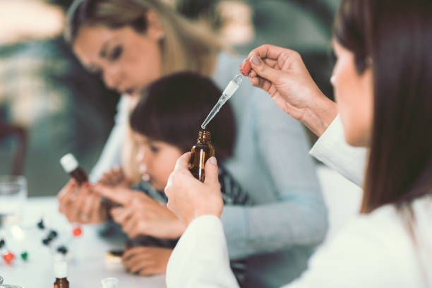 A group of people are sitting at a table holding bottles and a pipette.