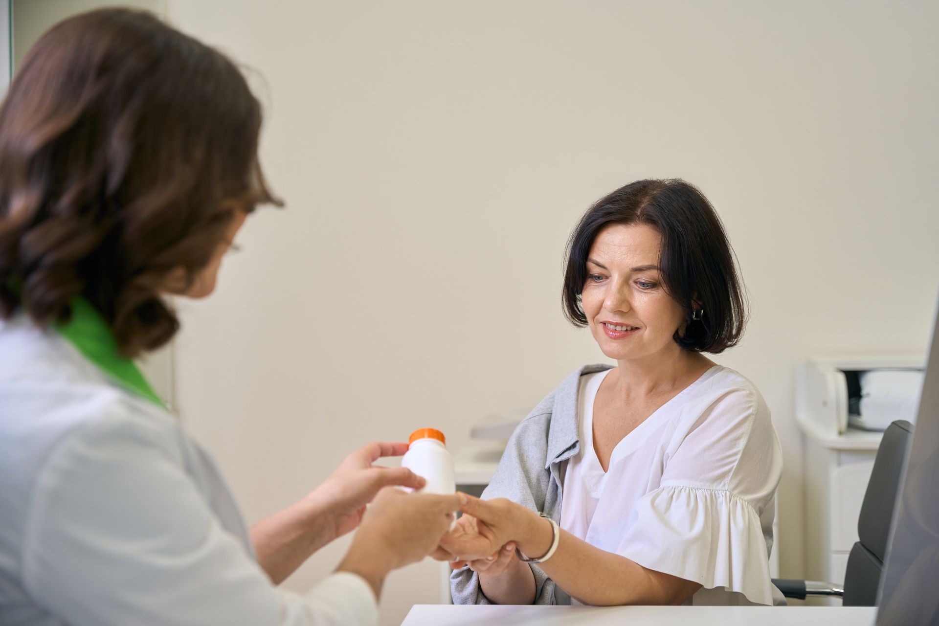 A doctor is giving a bottle of pills to a patient.