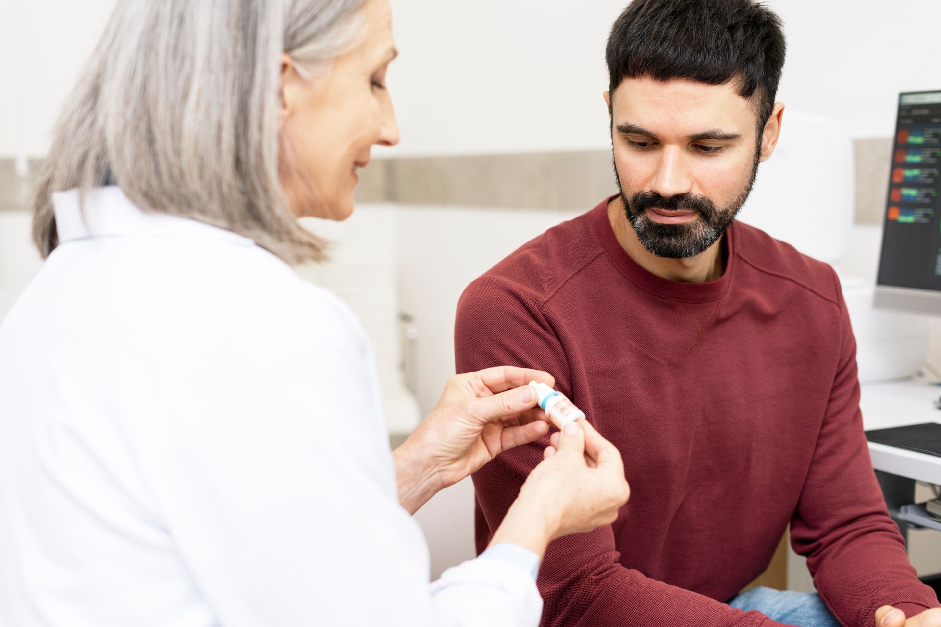A doctor is giving a man a pill in a hospital.
