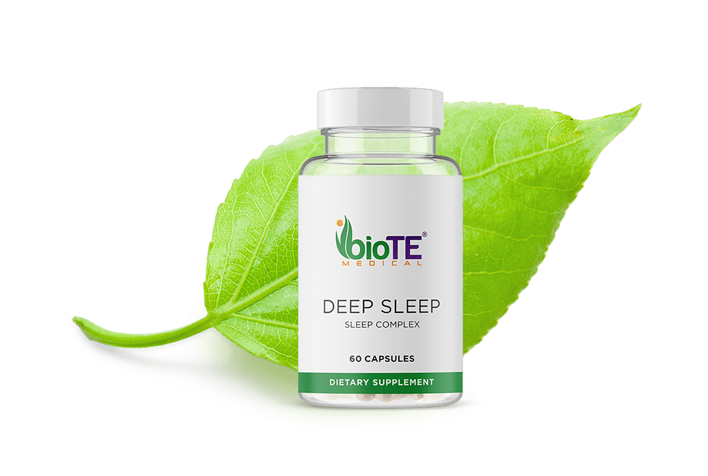 A bottle of biote deep sleep capsules is sitting on top of a green leaf.