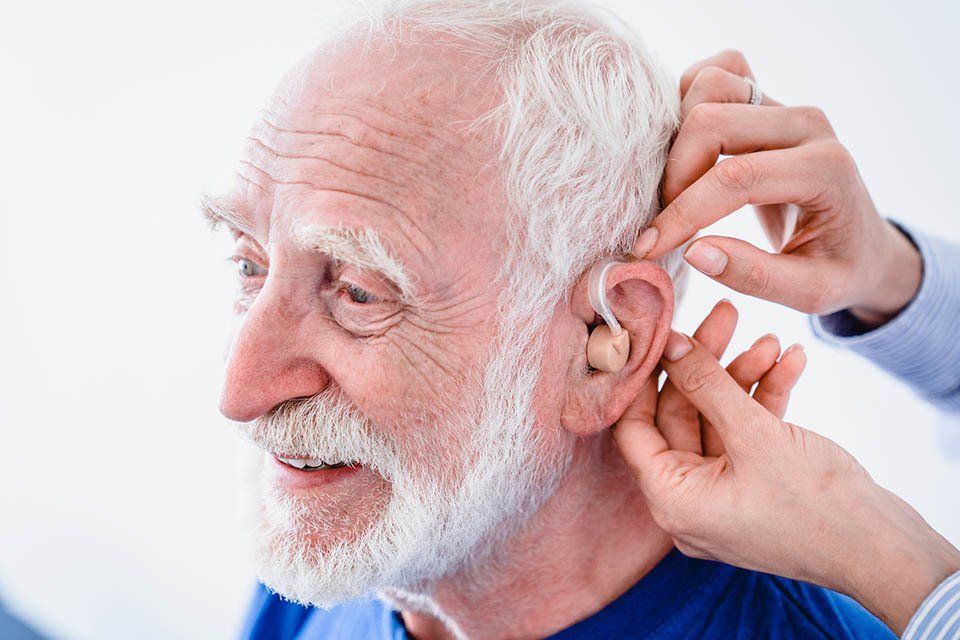 applicazione di apparecchio acustico su uomo anziano