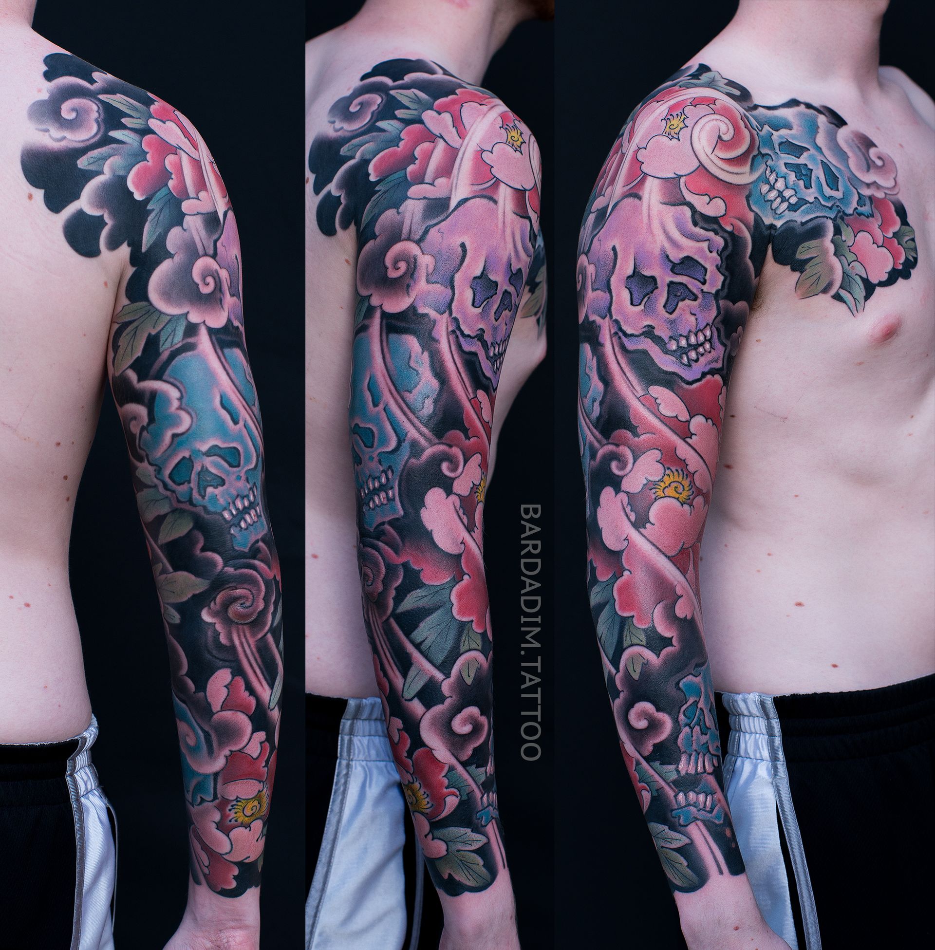 A man has a full sleeve tattoo of flowers and skulls