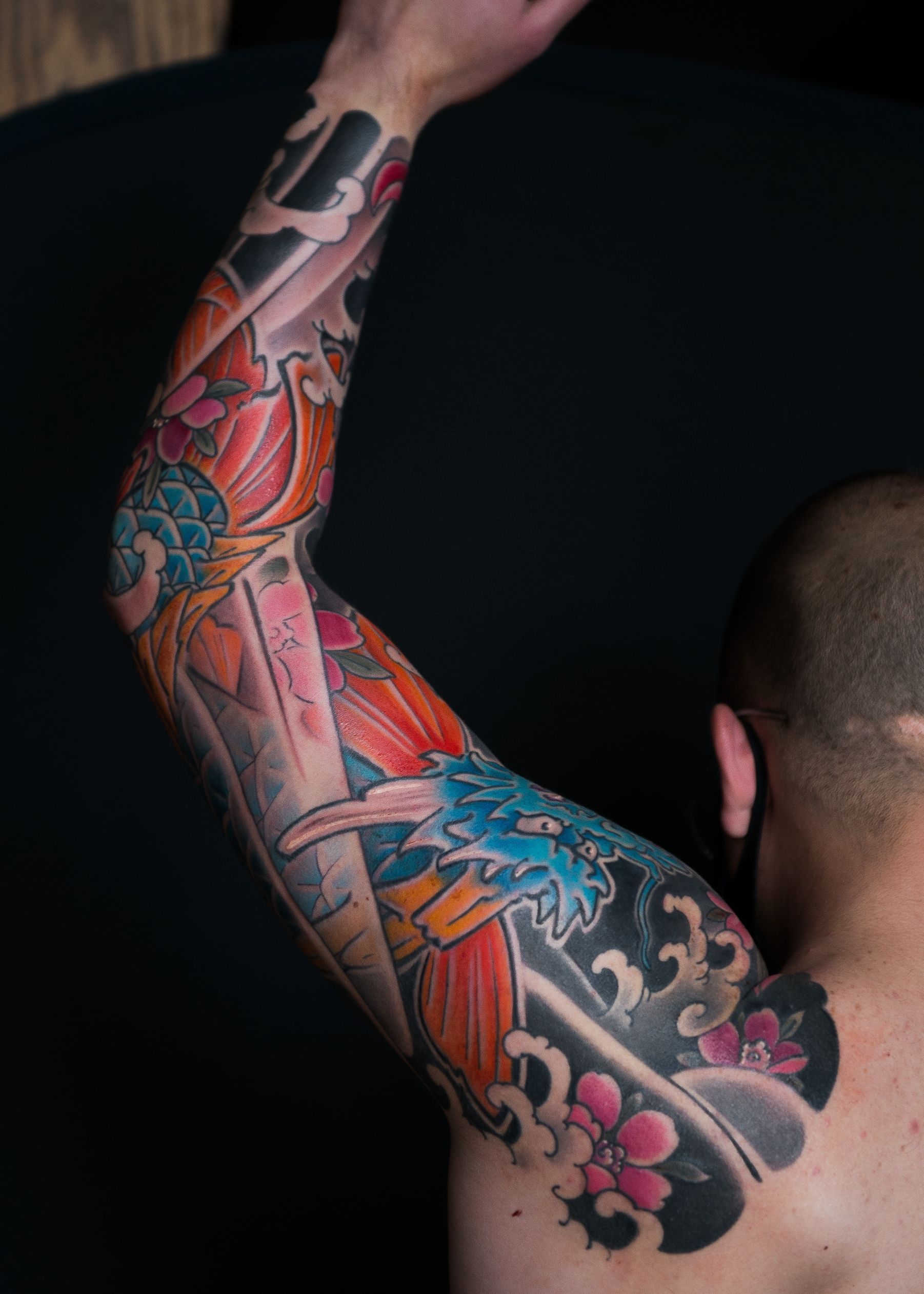 A man with a colorful tattoo on his arm and back.