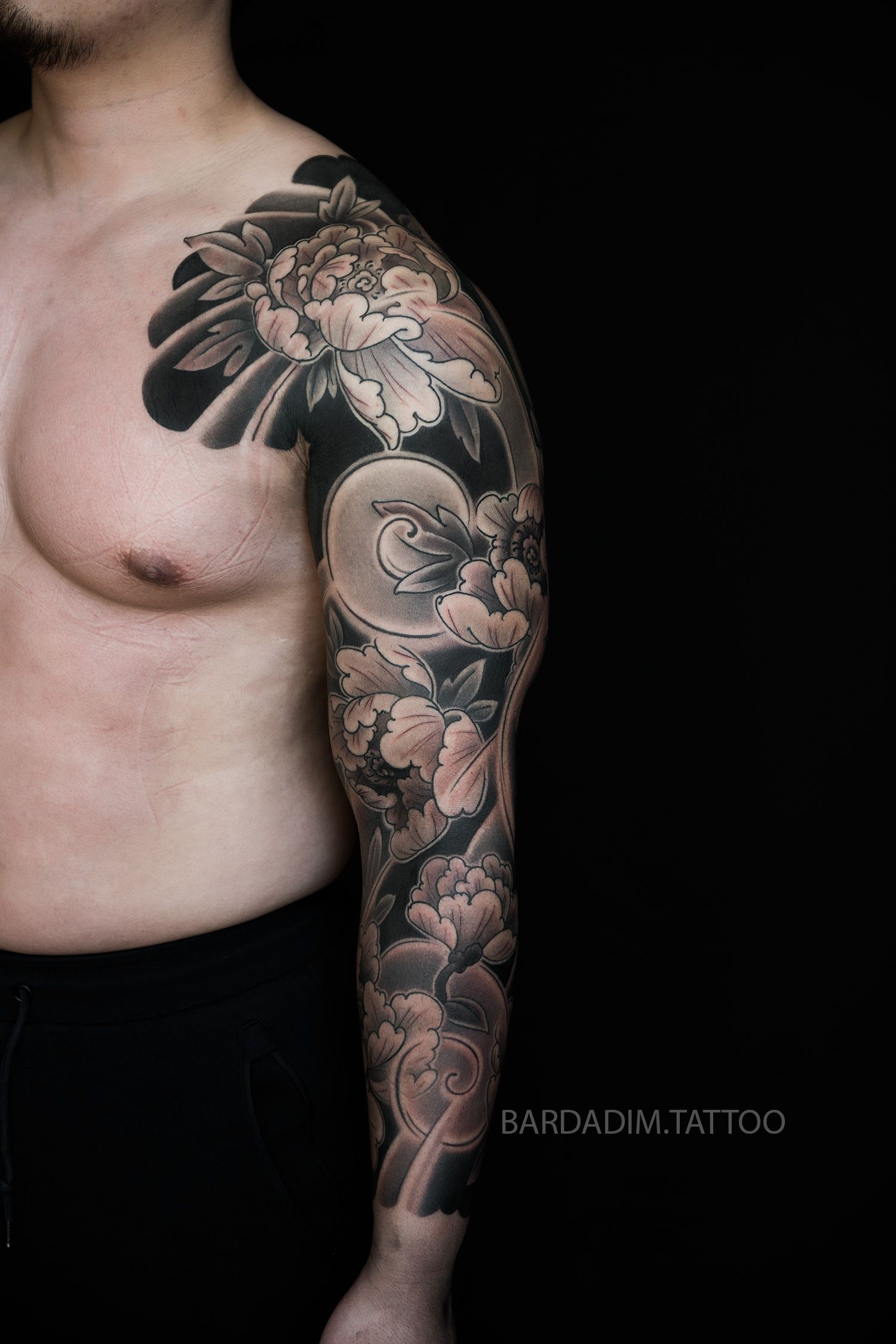A man with a full sleeve tattoo on his arm and chest.