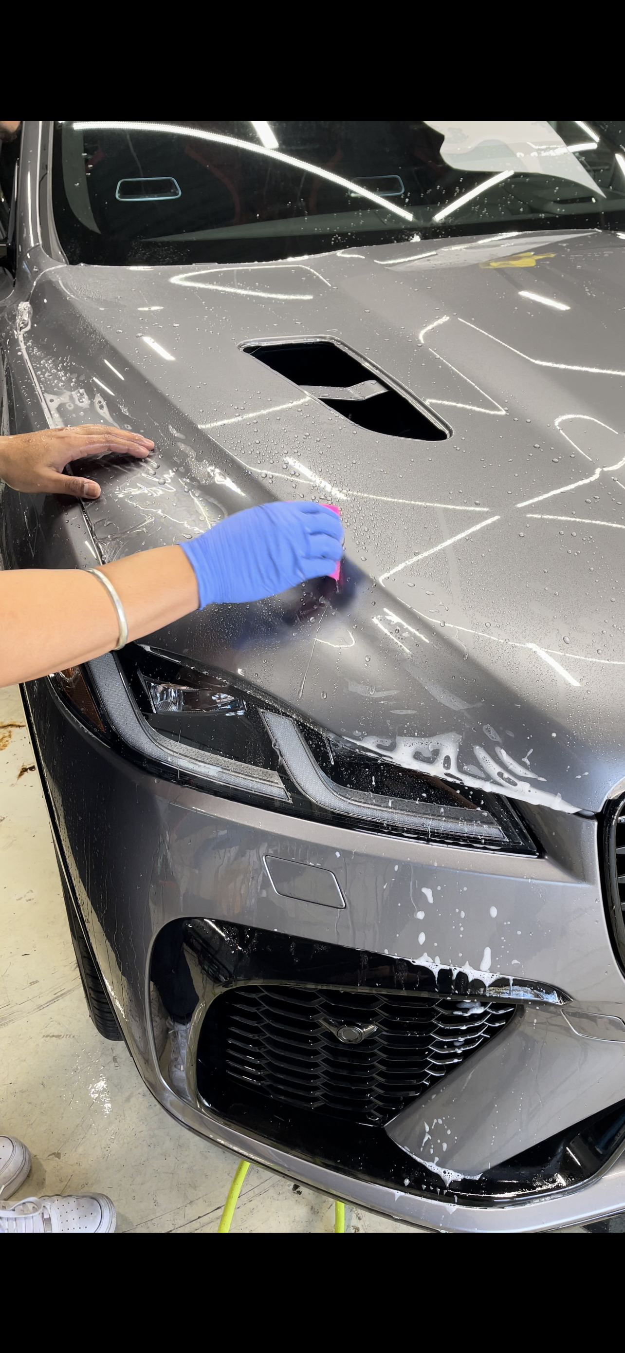 A person is cleaning the hood of a car.