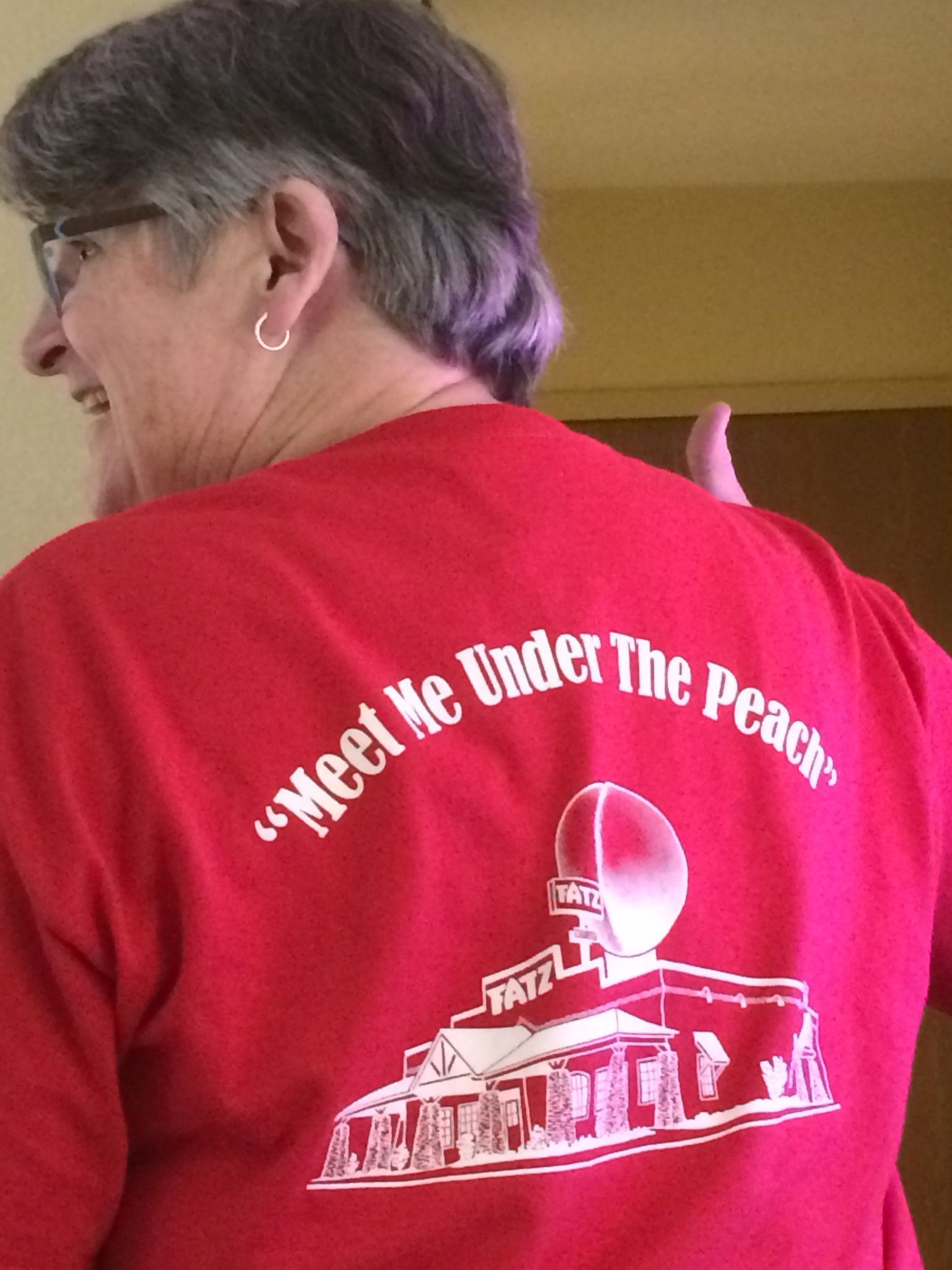 A person wearing a red t-shirt with a graphic of a peach-shaped water tower and the text 